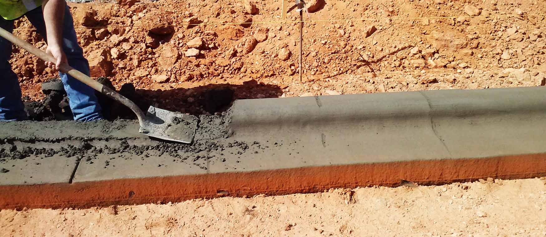 Worker shoveling concrete curb